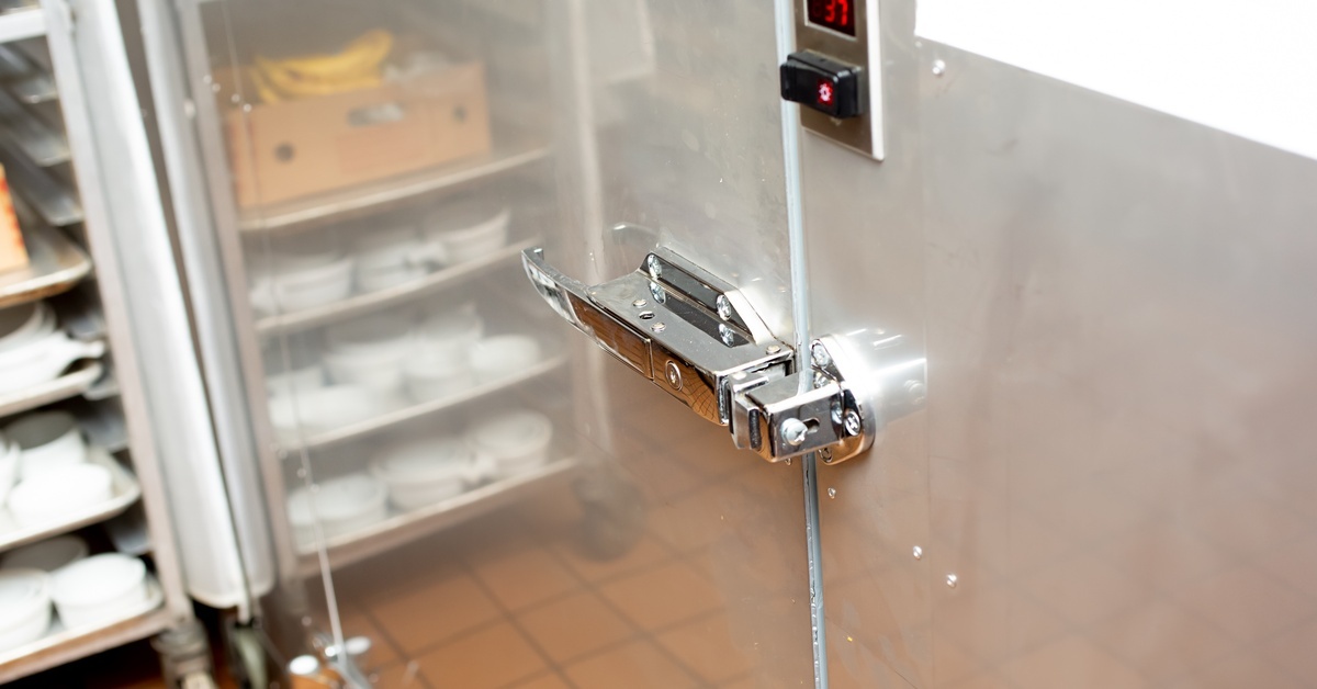 The sleek chrome door to a walk-in cooler. Above the latch is a thermostat panel that reads '37.'