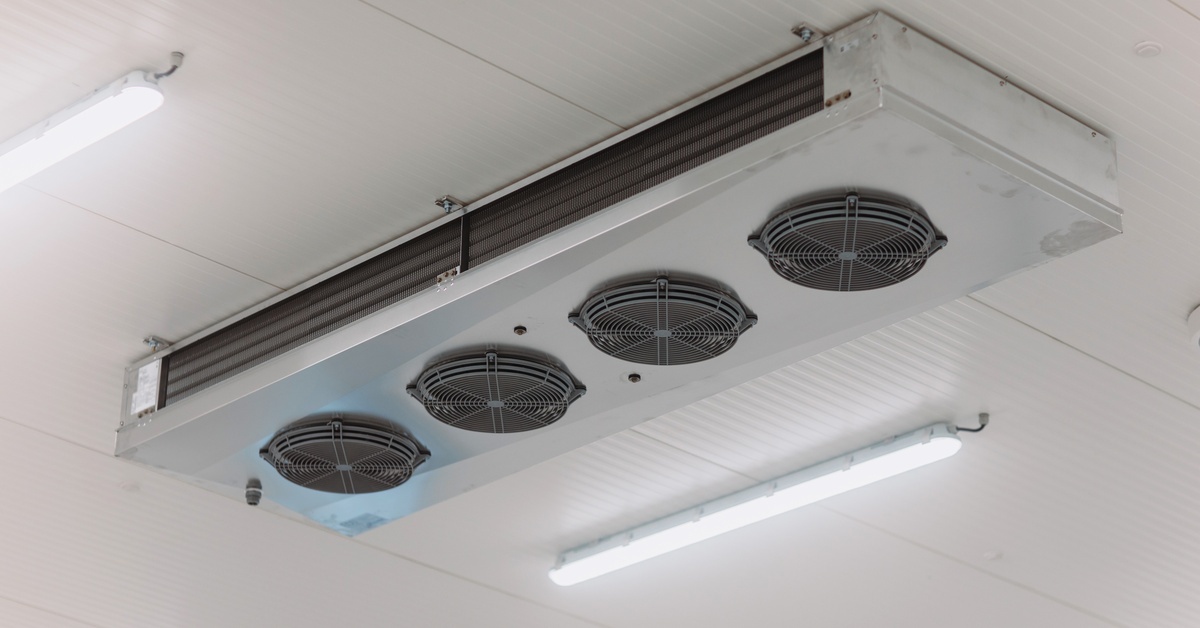 A ceiling mounted refrigeration unit. The sides have several vents while circular fans point toward the floor.
