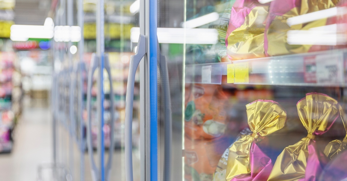 The cooler aisle of a grocery store with several coolers lined up together. The coolers are full of various food products.