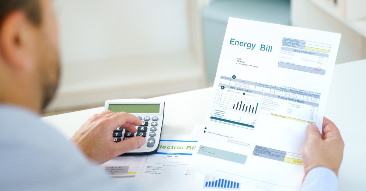 A person reviews an electric bill that shows several detailed graphs. They are also using a calculator.
